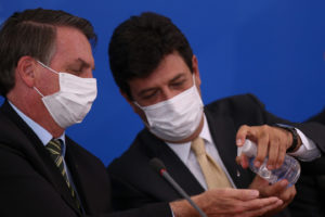 Ministro Luiz Henrique Mandetta (Saúde) aplica álcool em gel na mão do presidente Bolsonaro