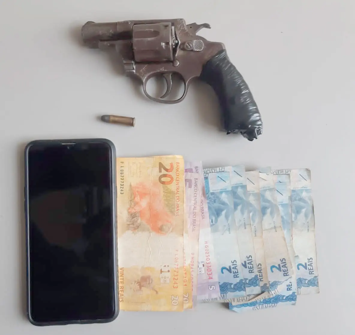 revólver calibre 32 com munição, celular e dinheiro