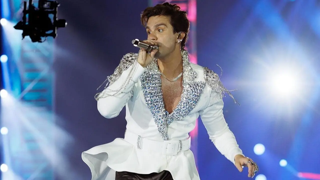 luan santana o cantor luan santana luan santana no palco luan santana cantando em show luan santana segurando o microfone de paletó branco cantando em show com fundo azu