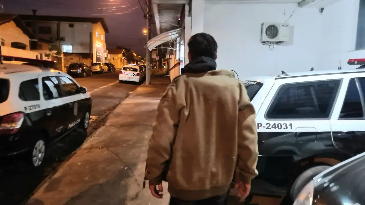 homem pega menina pelo braço em porta de escola