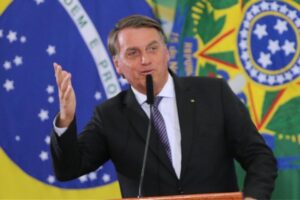 o ex-presidente jair messias bolsonaro em discurso com a bandeira do Brasil e das Forças Armadas ao fundo