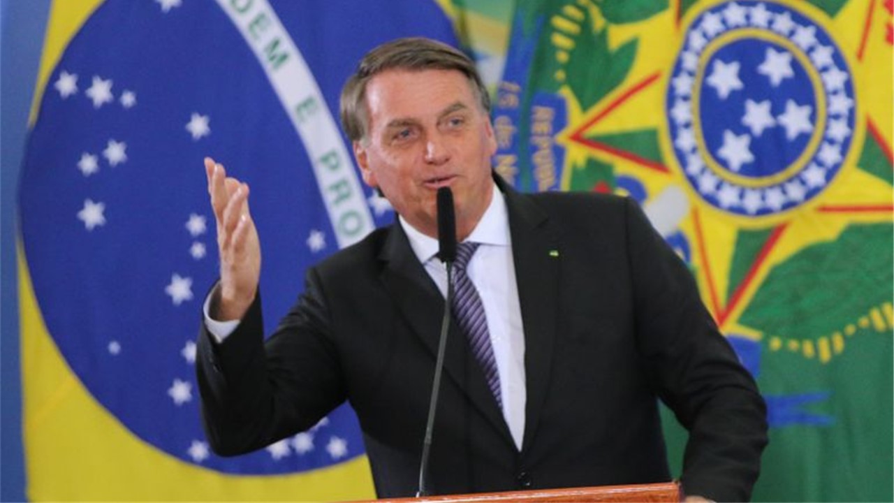 o ex-presidente jair messias bolsonaro em discurso com a bandeira do Brasil e das Forças Armadas ao fundo