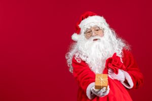 História do Papai Noel papai-noel-segurando-um-presente-de-uma-sacola-cheia-de-presentes-para-criancas-na-mesa-vermelha